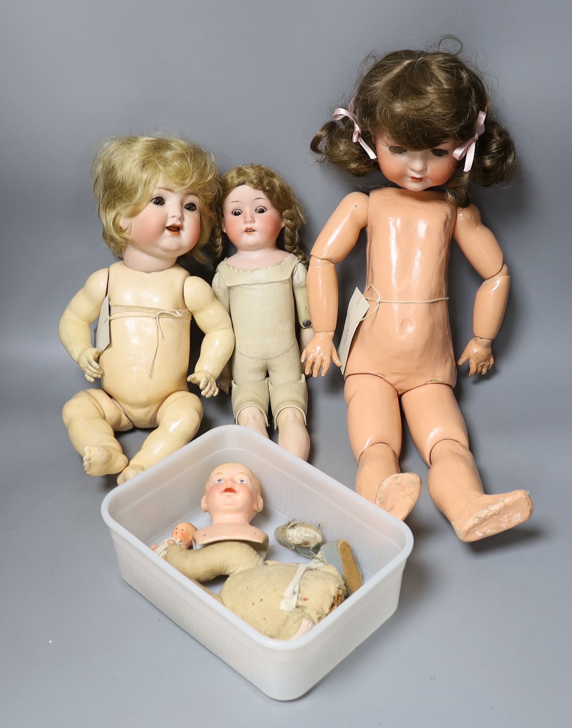 A kid leather bodied jointed limb open mouth Heubach bisque headed doll together with two other bisque headed dolls and a boy doll (damaged)